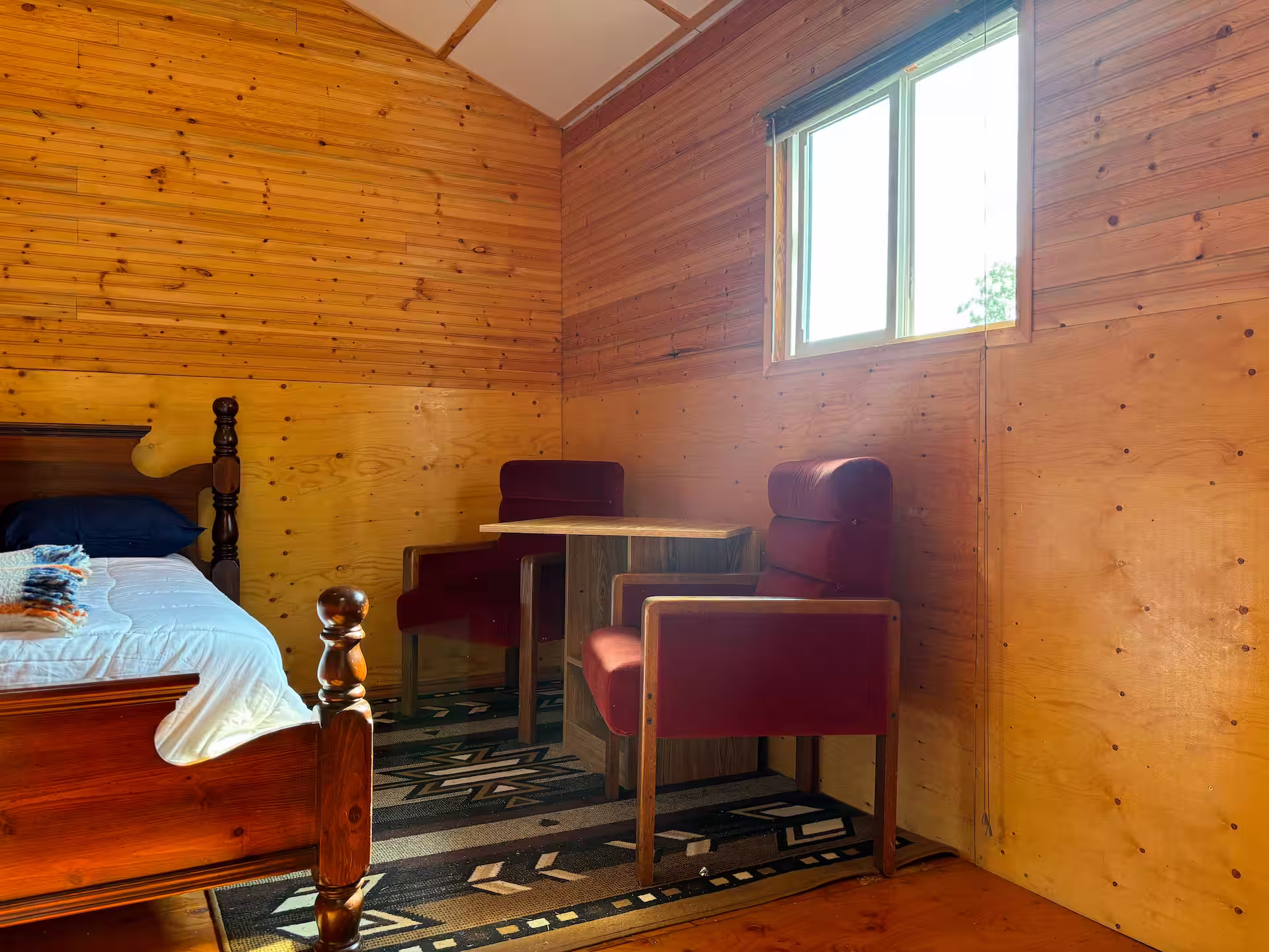 Two chairs, a bed, and the window looking out over the lake in the Eagle's Nest cabin.